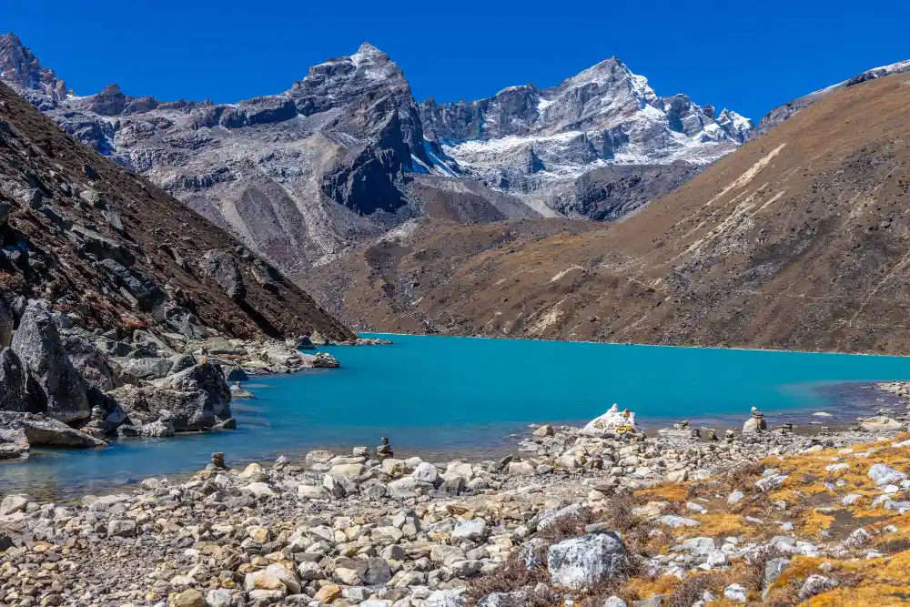 Turquoise glacial lake surrounded by rocky Himalayan mountains in Nepal