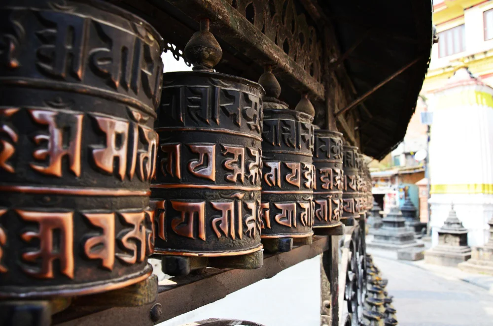 Row of carved Buddhist prayer wheels at a stupa in Kathmandu, Nepal